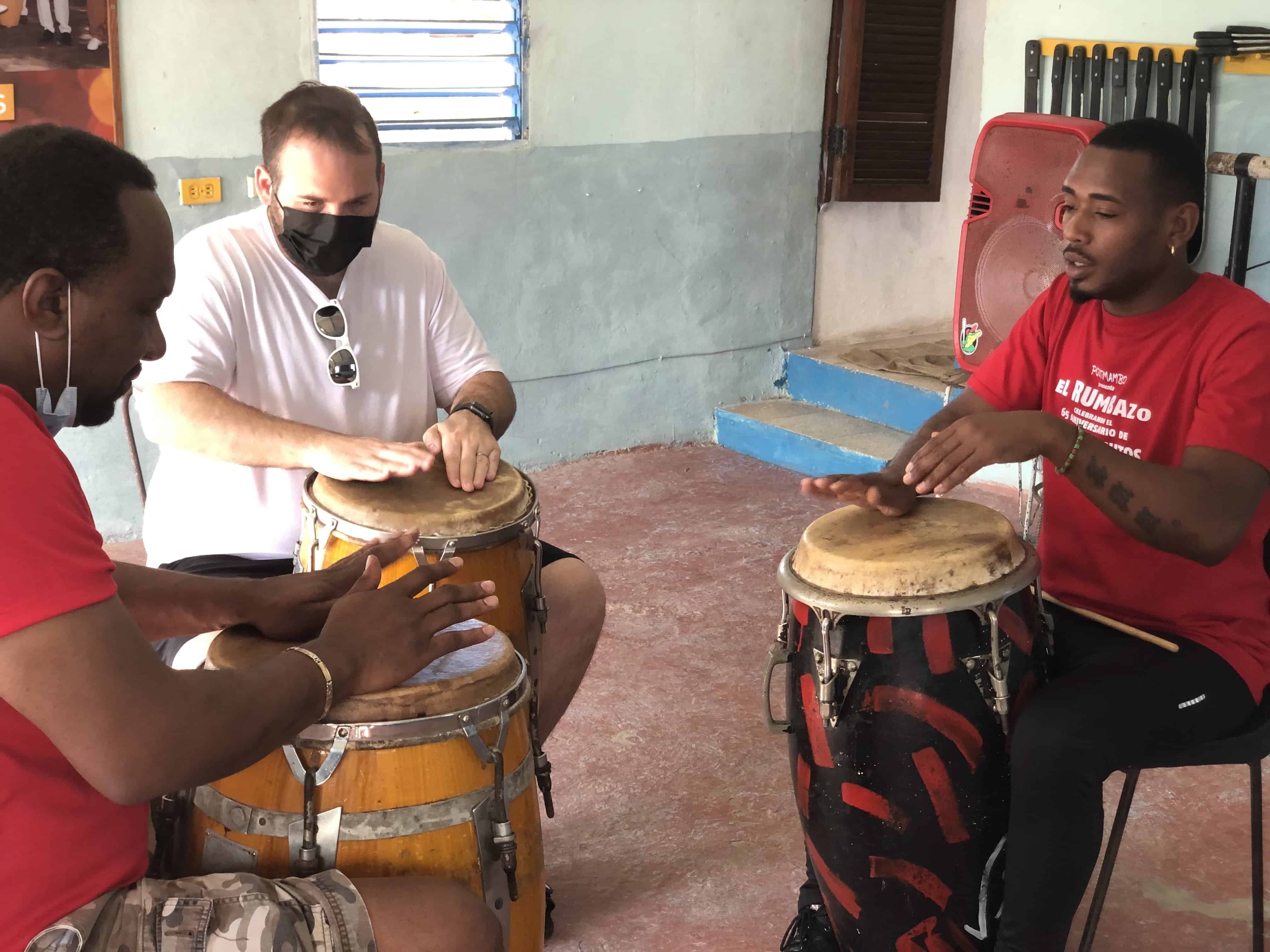 Participant and Cuban percussion instructors playing congas during a lesson
