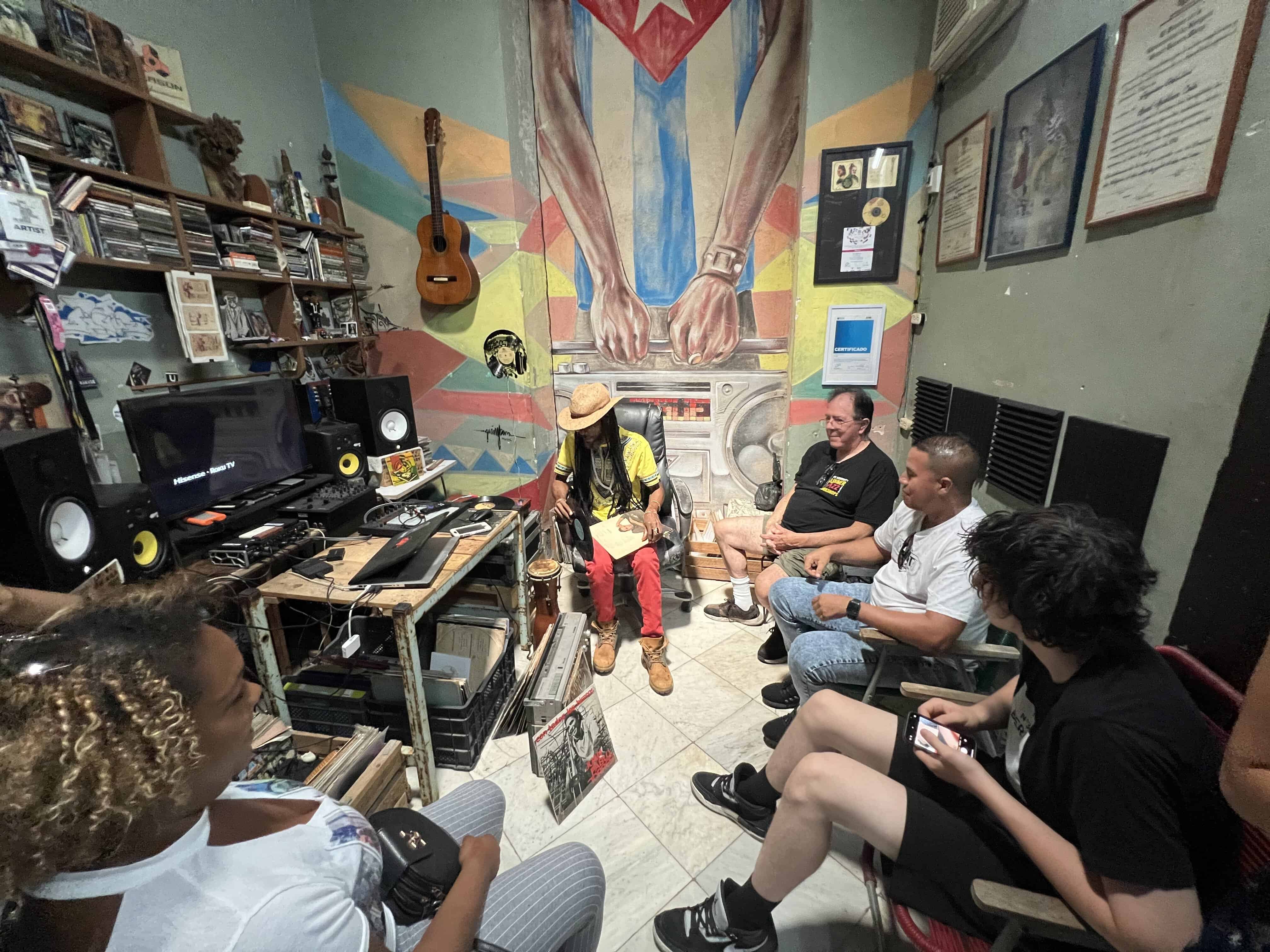 Small group discussing Cuban music with an educator in a room filled with instruments and records