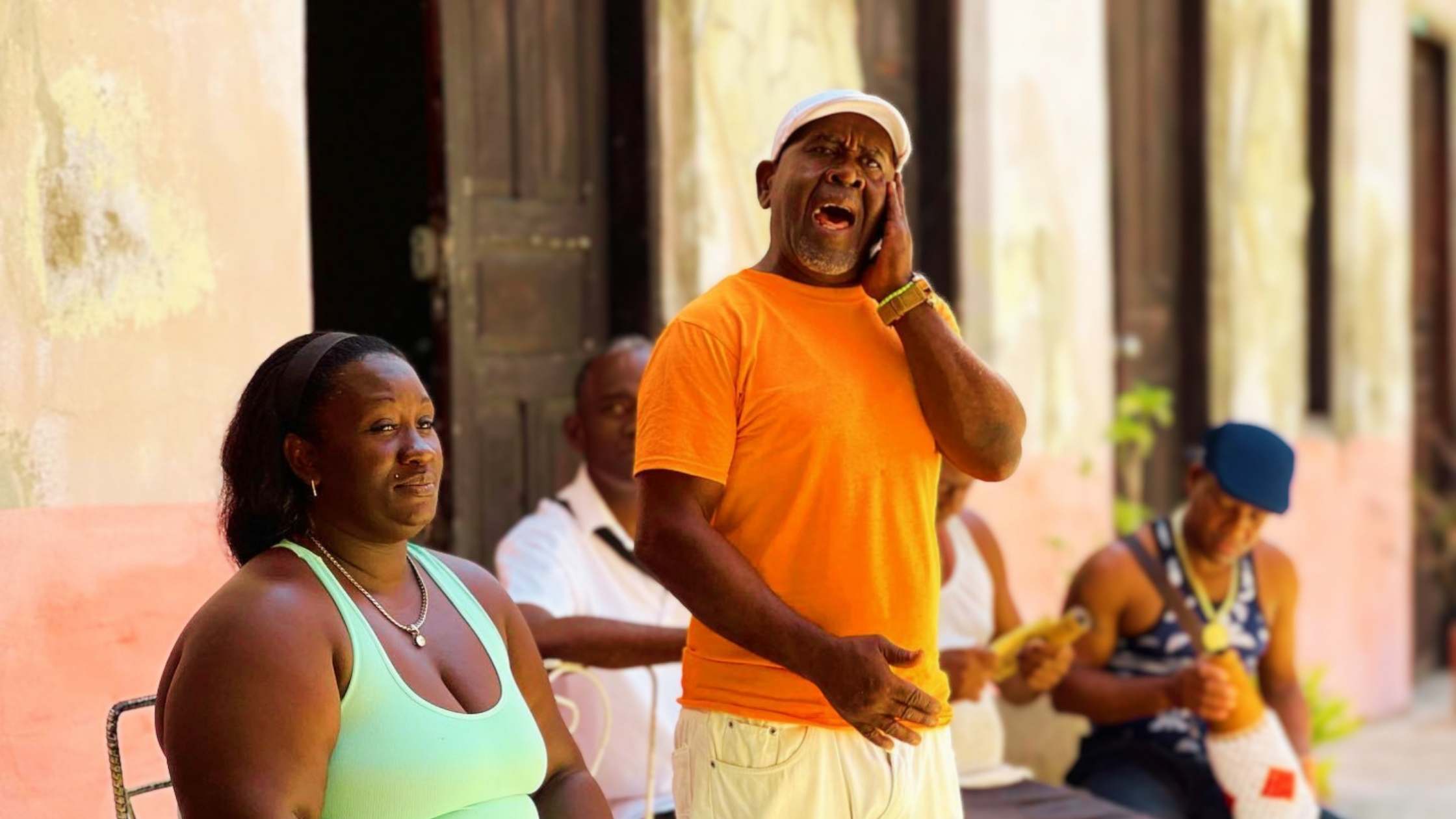 Singer performing outdoors in Santiago de Cuba, with musicians behind him.
