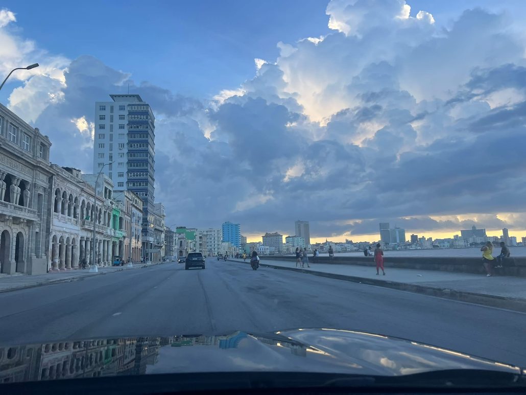Havana’s Malecón with waterfront buildings, pedestrians and traffic beneath a cloudy sky